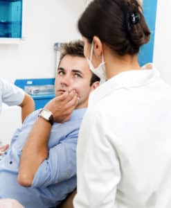 patient suffering TMJ at the dentist's office, talking to a dentist