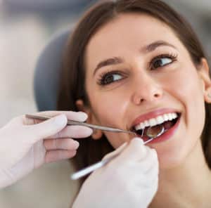 close up of woman's face while dentist is putting tools in her mouth