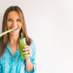 woman with stick of green organic celery and fresh homemade celery juice.