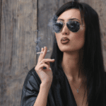 girl in a leather jacket and sunglasses smoking a cigarette