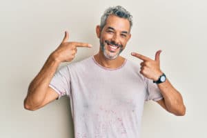 Middle-age-grey-haired-man-wearing-casual-clothes-smiling-cheerful-showing-and-pointing-with-fingers-teeth-and-mouth