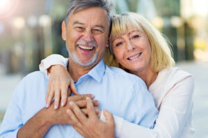 Happy smiling older couple improve their teeth with dental implants or dentures