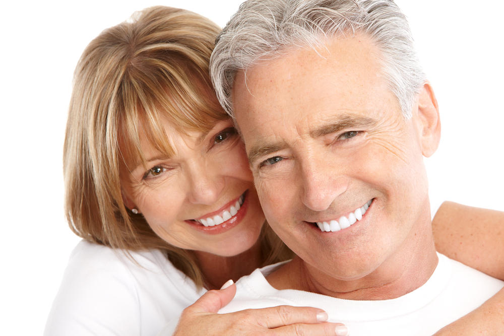 Happy couple smiles brightly with restored teeth thanks to All-on-4 dental implants/dentures.
