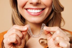 Attractive woman holds her Invisalign in front of her mouth.
