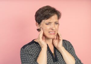 Woman grimaces in pain from a toothache, and wonders whether she has a dental emergency