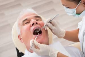 A senior man has his teeth examined by a female dentist.