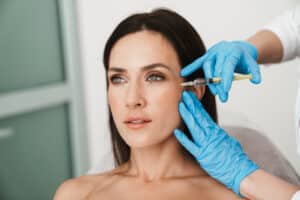 Woman at dental office receives Botox injection to reduce crow's feet.